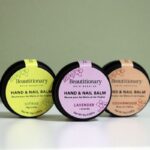 Minimalist photo featuring all three Beautitionary Hand and Nail Balm scents in metal tins, made with shea butter, black currant seed oil, and oat & kale protein for soft, hydrated hands and strong, healthy cuticles.